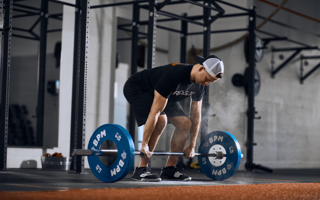 A man prepares to Olympic lift a barbell at BPM, demonstrating focus and proper technique in a gym setting